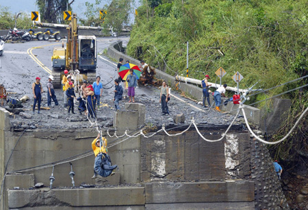 A rescuer moves along cables slung above a destroyed bridge so as to get into the village of Xinkai and rescue trapped villagers in Kaohsiung of Taiwan, August 12, 2009. The village was hit by debris flow caused by typhoon Morakot and casualties was estimated at at least 32. [Xinhua]