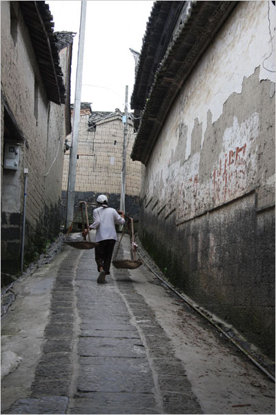 A man with a shoulder pole walks on the pebble road in a Heshun lane. [Photo: CRIENGLISH.com /Bao Congying]