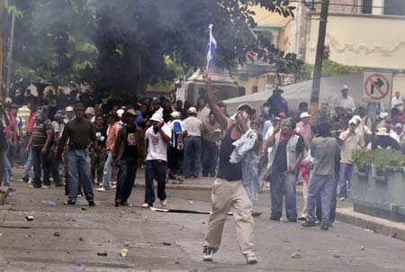 Supporters of ousted Honduran President Manuel Zelaya throw stones to policemen and soldiers during a protest in Tegucigalpa, capital of Honduras, on Aug. 12, 2009. Hundreds of Honduras people were arrested since the protest Sunday for demanding Zelaya's restitution as president of the country. (Xinhua/Rafael Ochoa)