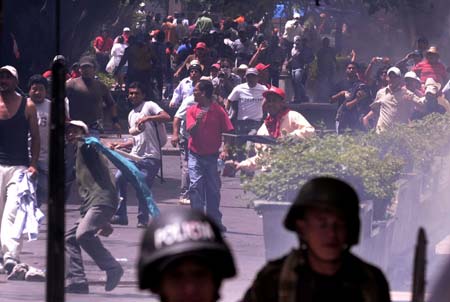 Supporters of ousted Honduran President Manuel Zelaya throw stones to policemen and soldiers during a protest in Tegucigalpa, capital of Honduras, on Aug. 12, 2009. Hundreds of Honduras people were arrested after the protest Sunday for demanding Zelaya's restitution as president of the country. (Xinhua/Rafael Ochoa)