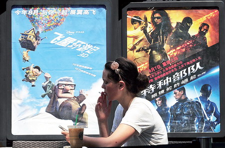 A woman checks messages on her cell phone yesterday in front of promotional posters for foreign-made movies in Beijing. China said it “regretted” a World Trade Organization decision ordering it to ease some of its restrictions on foreign films, music and print.