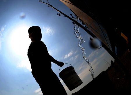 A farmer waters the dried field in Fuxin city, northeast China's Liaoning Province, Aug. 14, 2009.(