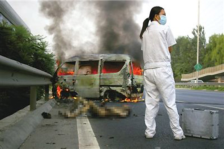 A medical staff member works at the site of a minibus fire accident in Beijing, August 13, 2009. [Xinhua] 