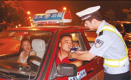A policeman tests a taxi driver to determine whether he is driving under the influence of alcohol on Saturday evening in Huaibei, Anhui province.(Photo Source:China Daily)