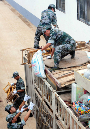 Soldiers help to unload belongings of farmers, relocated for the South-to-North Water Diversion Project, at a newly built village in Xuchang, in central China's Henan province, August 16, 2009. [Xinhua]