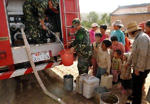 Farmers and children wait to collect water from a water wagon in a drought-hit village in Tianping Township of Xiji County, northwest China's Ningxia Hui Autonomous Region, August 14, 2009. [Xinhua]