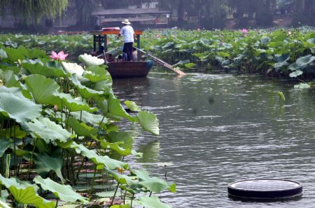 A boat moves past a solar energy water cleaning device located in a lake in Zizhuyuan Park in Beijing, capital of China, Aug. 14, 2009. More than ten such devices were put into use here recently. [Chen Xiaogen/Xinhua]