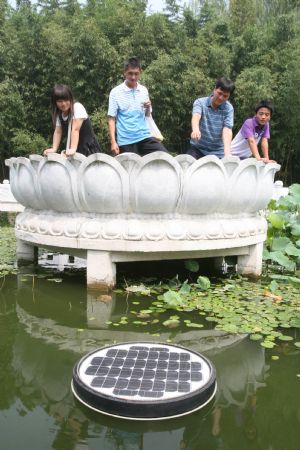 Visitors curiously watch a solar energy water cleaning device located in a lake in Zizhuyuan Park in Beijing, capital of China, Aug. 14, 2009. [Chen Xiaogen/Xinhua]