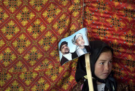 An ethnic Hazara girl attends a campaign rally for Afghan President Hamid Karzai in Bamiyan, central Afghanistan August 16, 2009. Pictured in the campaign image is running mate former Vice-President Mohammad Qasim Fahim (L) and President Hamid Karzai. Afghanistan is scheduled to hold its presidential elections on August 20.