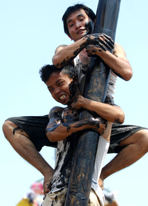 Two contestants help one another to climb a greasy pole to reach a prize hung at the top during the celebrations of Indonesia's Independence Day in Jakarta Aug. 17, 2009. Indonesia on Monday celebrated its 64th anniversary of independence. (Xinhua/Yue Yuewei)
