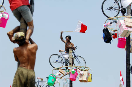  A contestant gets a prize hung at the top of a greasy pole during the celebrations of Indonesia's Independence Day in Jakarta Aug. 17, 2009. Indonesia on Monday celebrated its 64th anniversary of independence. (Xinhua/Yue Yuewei)