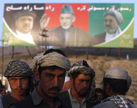Afghan labourers wait to be hired for work in front of a picture of incumbent Hamid Karzai (C) in Kabul August 18, 2009.The Afghan presidential election will take place on August 20.