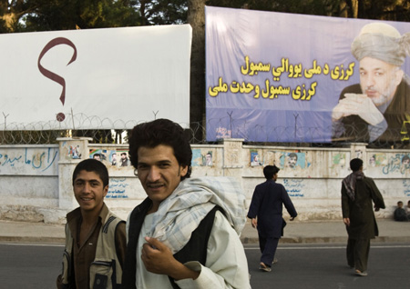 Afghans walk past election billboard of Afghanistan's President Hamid Karzai in Herat, western Afghanistan August 18, 2009.