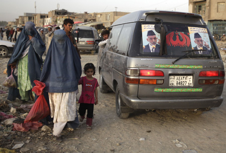 People walk past a campaign car for President Hamid Karzai in Kabul, August 17, 2009. 