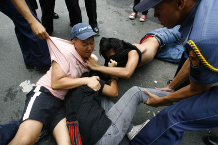 Policemen arrest a student protester during a scuffle as protesters reached the gates of the Malacanang compound in suburban Manila, Aug. 19, 2009. More than a dozen protesters were arrested and some injured as they scuffled with police while breaching through security gates during a demonstration against alleged corruption in the government of Philippine President Gloria Macapagal-Arroyo.(Xinhua/Luis Liwanag)