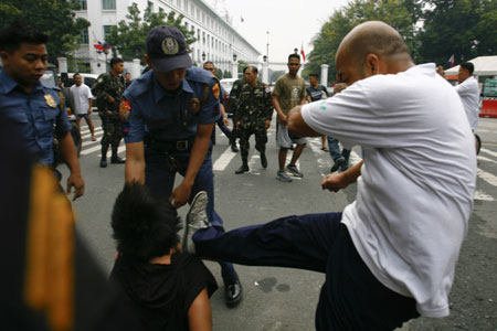 A Philippine protester is kicked by a plainclothes police officer after students stormed the gates of the Malacanang Presidential Palace in Manila, Aug. 19, 2009. More than a dozen protesters were arrested and some injured as they scuffled with police while breaching through security gates during a demonstration against alleged corruption in the government of Philippine President Gloria Macapagal-Arroyo.(Xinhua/Luis Liwanag)