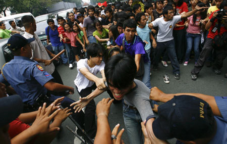 Student protesters hold one of their classmates as police try to arrest him upon reaching the gates of the Malacanang compound in suburban Manila, Aug. 19, 2009. More than a dozen protesters were arrested and some injured as they scuffled with police while breaching through security gates during a demonstration against alleged corruption in the government of Philippine President Gloria Macapagal-Arroyo.(Xinhua/Luis Liwanag)(