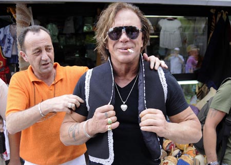 U.S. actor Mickey Rourke (R) tries a piece of traditional Bosnian clothing in the old section of Sarajevo August 19, 2009. Rourke arrived in the Bosnian capital as a guest of the 15th Sarajevo Film Festival.