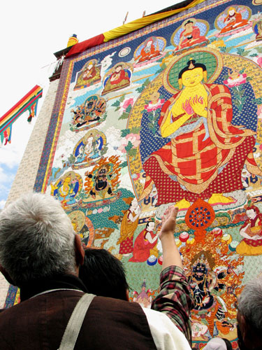 Tibetans and tourists view a huge Tangka, a religious silk embroidery or painting unique to Tibet, during the Shoton Festival at Drepung Monastery on the outskirts of Lhasa, Tibet Autonomous Region August 20, 2009. [Photo: Chang Chuan/CFP]