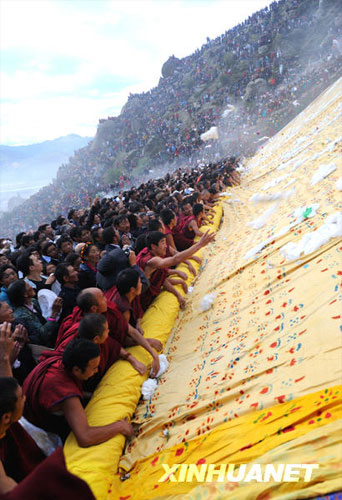 Visitors and lamas participated in the unveiling of a giant tangka, displaying the image of Sakyamuni, the founder of Buddhism, in Drepung Monastery in Lhasa, Tibet Autonomous Region's capital, on Thursday morning, August 20, 2009. The week-long Shoton Festival kicked off in Lhasa on Thursday. [Photo: Xinhuanet] 