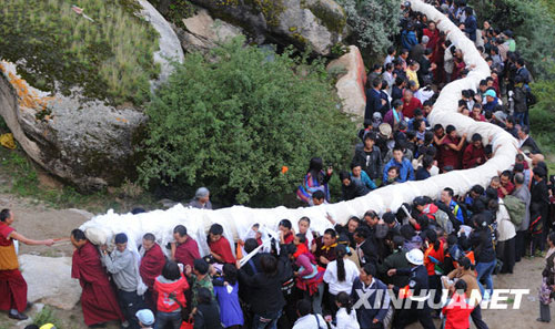 Lamas and residents carry the giant tangka to be unveiled in Drepung Monastery in Lhasa, Tibet Autonomous Region's capital, on Thursday morning, August 20, 2009. The week-long Shoton Festival kicked off in Lhasa on Thursday. [Photo: Xinhuanet] 