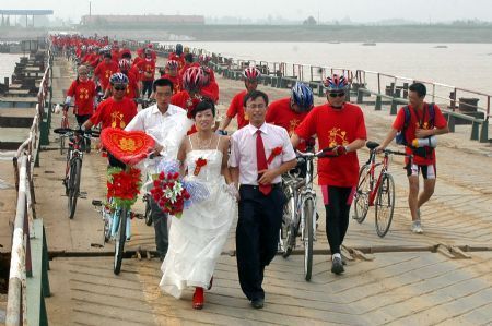 Bridegroom Tong Yanliang and Bride Li Jingjing walk across the float bridge over the Yellow River in Binzhou City of east China's Shandong Province, Aug. 19, 2009.[Li Rongxin/Xinhua]