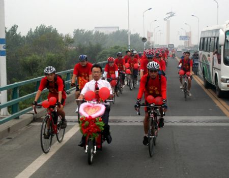 Bridegroom Tong Yanliang ride a two-seat bicycle to the home of bride accompanied by their friends in Binzhou City of east China's Shandong Province, Aug. 19, 2009.[Li Rongxin/Xinhua]