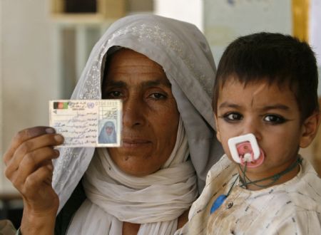 An Afghan woman shows her identity card after voting for her candidate during presidential and provincial elections in the southern Afghan city of Kandahar, August 20, 2009.[Xinhua/Reuters]