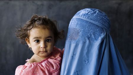 An Afghan woman carries a girl while standing in line at a polling station in Herat, western Afghanistan August 20, 2009.[Xinhua/Reuters]