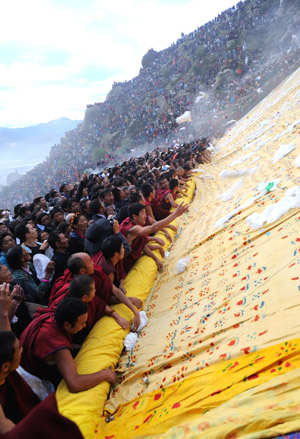 Lamas and locals attend the Buddha Thangka painting unfolding ceremony in Zhebung Monastery on the outskirts of Lhasa, capital of southwest China's Tibet Autonomous Region, on Aug. 20, 2009.[Chogo/Xinhua] 