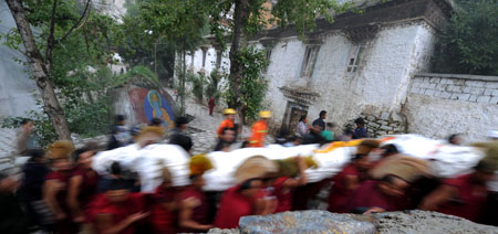 Lamas and locals carry a huge-sized Buddha Thangka painting to the site where the Buddha Thangka painting unfolding ceremony is held at Sera Monastery in Lhasa, capital of southwest China's Tibet Autonomous Region, on Aug. 20, 2009.[Chogo/Xinhua] 