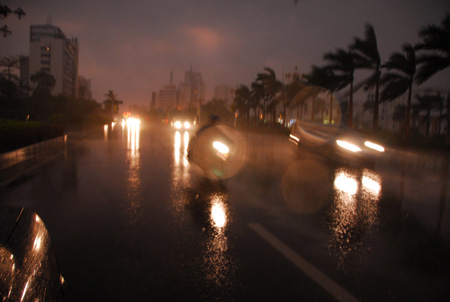 Vehicles and pedestrians trudge ahead against the rainfalls in the dusk, as an hour-long thundershower formed by the strong convective weather hit the urban areas of Qingyuan City, south China's Guangdong Province, Aug. 23, 2009. (Xinhua/Li Zuomiao) 
