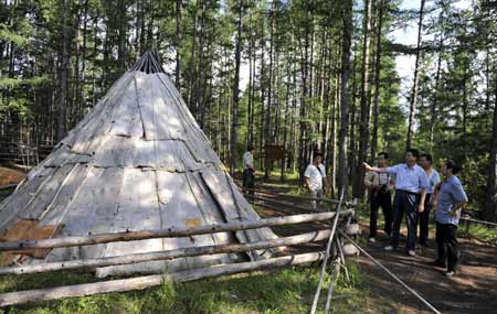 Tourists view a bark house used to be home of Owenke ethnic group in Genhe City of north China's Inner Mongolia Autonomous Region, on Aug. 16, 2009.[Li Xin/Xinhua]