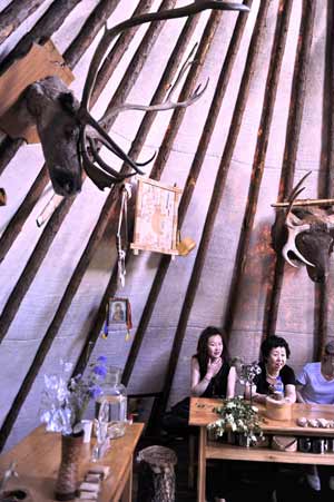 Visitors experience a bark house used to be home of Owenke ethnic group in Genhe City of north China's Inner Mongolia Autonomous Region, on Aug. 16, 2009.[Li Xin/Xinhua]