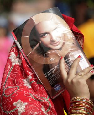 A women uses a magazine to shield her face from the sun while queuing up at Pashupati Nath Temple during celebrations of the 'Teej' festival in Kathmandu August 23, 2009.[Xinhua/Reuters]