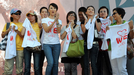 Pop singer Coco Lee (C) poses for photos with fans on a promotion event of her new album in Taipei, southeast China's Taiwan Province, Aug. 23, 2009, during which she raises donations for the typhoon Morakot hit area in Taiwan by rummage sales of T-shirts designed by herself with a designing group. [Xinhua]