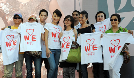 Pop singer Coco Lee (C) poses for photos with fans on a promotion event of her new album in Taipei, southeast China's Taiwan Province, Aug. 23, 2009, during which she raises donations for the typhoon Morakot hit area in Taiwan by rummage sales of T-shirts designed by herself with a designing group. [Wu Ching-teng/Xinhua]