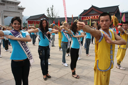 Contestants of Miss Tourism Queen International 2009 learn wushu from the students of Shaolin Temple Tagou Wushu School in Dengfeng, central China's Henan Province, Aug. 23, 2009. [Chen Daishu/Xinhua]