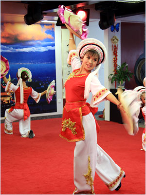 Dancers of Bai people are performing on the board while serving travelers with three cups of tea. [Photo: CRIENGLISH.com/ Xu Liuliu]