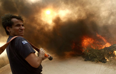 A firefighter prepares to battle a forest fire in Grammatiko village northeast of Athens August 22, 2009. A large wildfire raged out of control on the outskirts of Athens on Saturday, burning several homes and thousands of acres of forest. 