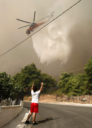 A fire-fighting helicopter drops water over a forest fire in Grammatiko village, about 48km northeast of Athens, August 22, 2009.