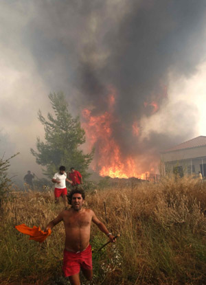 Locals run to escape a forest fire in Grammatiko village, about 48km northeast of Athens, August 22, 2009. 