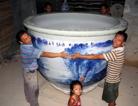 Four adults stretch out their arms to enfold a colossal crock of black and white porcelain, which stands at 1.36 meters in height, measures 6.8 meters in perimeter, with a caliber of 2 meters and a weight of over 1,500 kg, in Jingdezhen, east China's Jiangxi Province, Aug. 24, 2009.[Shi Weiming/Xinhua]