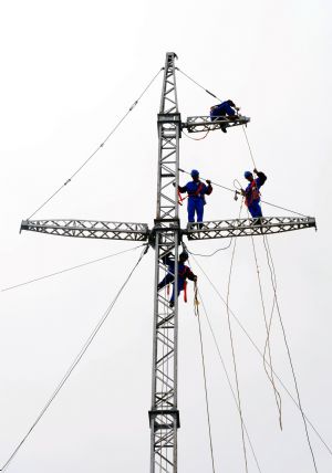 Workers operate on restoring the iron tower for the power transmission in an emergent repair drilling to the 110 kilowatts power transmission line, organized by the Lianyungang City's Power Supply Company, in a bid to check up its staff's emergency-dealing and normalcy-restoring capability to ensure the safe and orderly electricity supply of the whole city, in Lianyungang, east China's Jiangsu Province, Aug. 25, 2009. (Xinhua/Geng Yuhe)