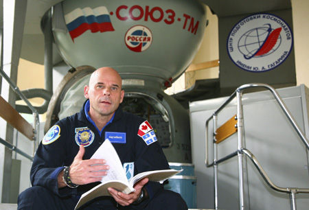 Guy Laliberte prepares for exercises in front of a landing capsule during a training session in the International Space Station (ISS) at the Star City space centre outside Moscow, August 25, 2009.[Xinhua/Reuters]