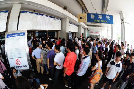 Passengers wait in line to buy train tickets at Changsha Railway Station in Changsha, central China's Hunan Province, on Aug. 25, 2009. Changsha Railway Station has witnessed a travel peak since more and more students began to return to schools after the summer vacation. [Long Hongtao/Reuters]