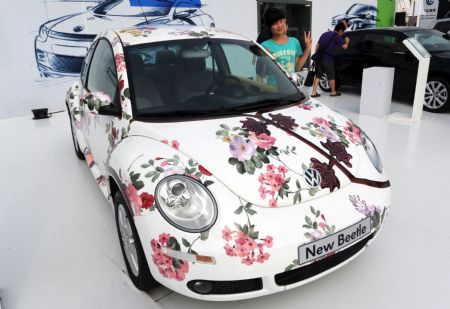 A visitor poses for camera with a coloured Volkswagen Beetle at the auto exhibition of International Beer Festival in Qingdao, east China's Shandong Province, Aug. 25, 2009. The newly coloured Bettle attracted many visitors. [Xinhua]