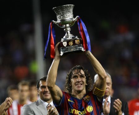 Barcelona's captain Carles Puyol raises the trophy after the team defeated Athletic Bilbao in the Spanish Super Cup final second leg soccer match at Nou Camp stadium in Barcelona August 23, 2009.[Xinhua/Reuters]