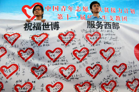 Two postgraduate volunteers unfurl the streamer with the collective signatures of volunteers who are about to set out on their obligation as assisting tutors during the setting-off ceremony, in Guiyang, southwest China's Guizhou Province, Aug. 25, 2009.[Xinhua]