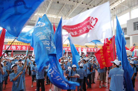 Postgraduate volunteers who are to set out on their obligation as assisting tutors wave their banners during the setting-off ceremony in Guiyang, southwest China's Guizhou Province, Aug. 25, 2009.[Xinhua]